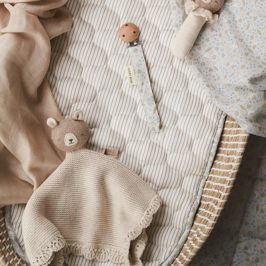 Konges Sløjd baby comforter, pacifier clip, and rattle in beige organic cotton basket