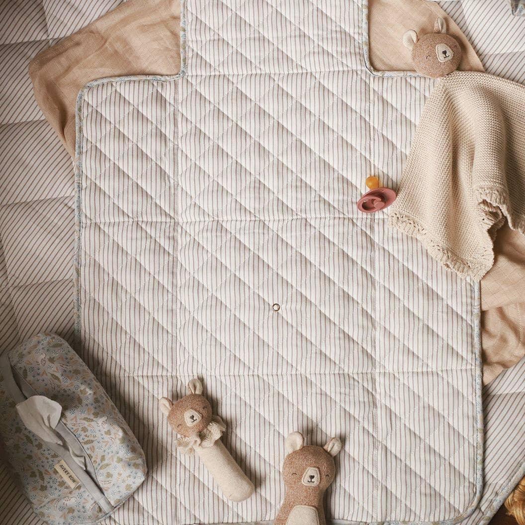 Konges Sløjd quilted cotton changing mat in beige stripe, with bear plush toys and baby essentials.