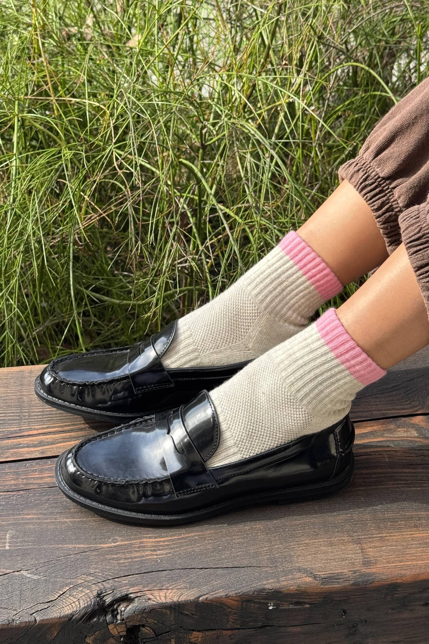 Marge Sherwood black patent leather loafers on wood with beige pink-trim socks.