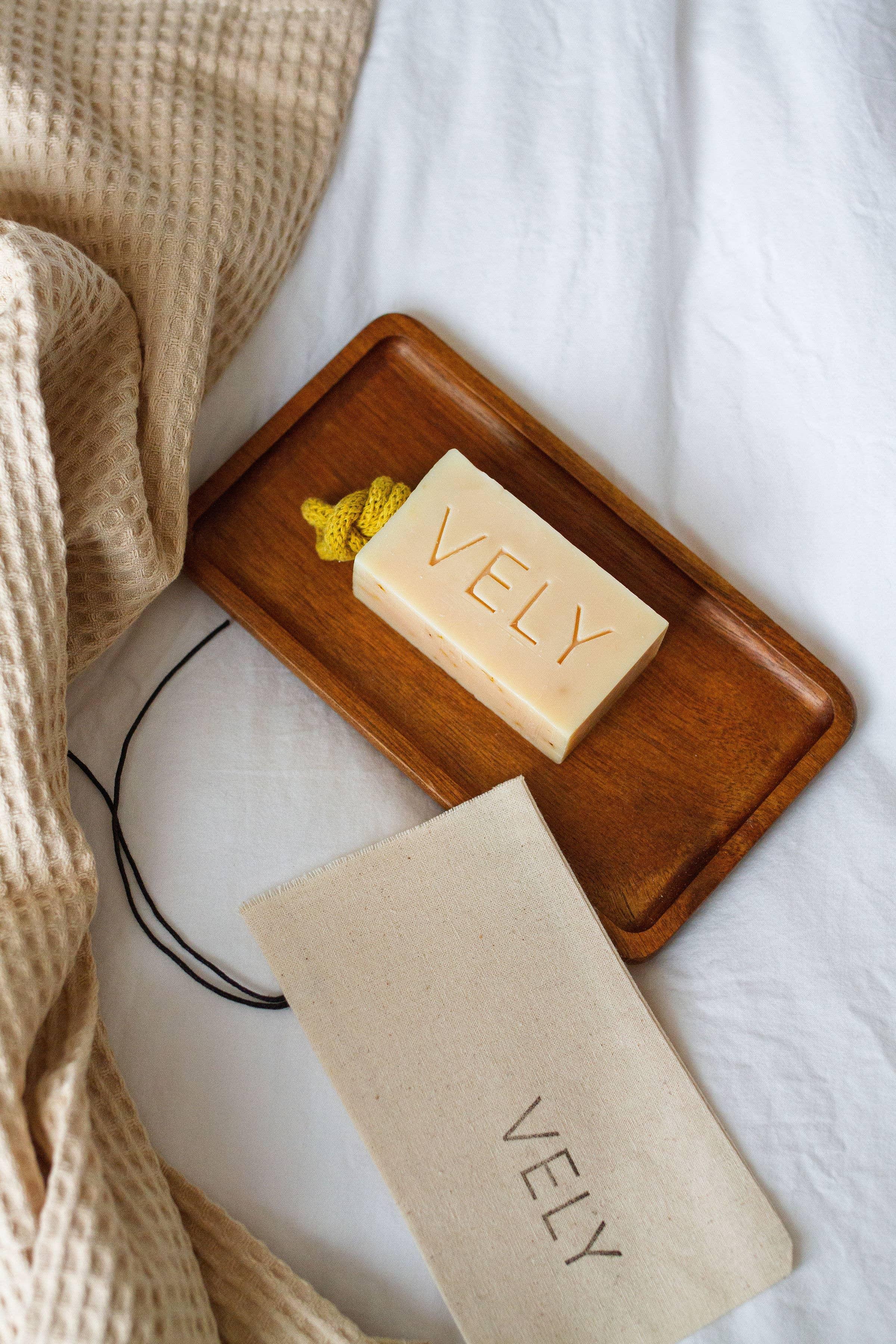 VELY natural beige soap bar with yellow rope on wooden tray, cotton pouch and waffle towel