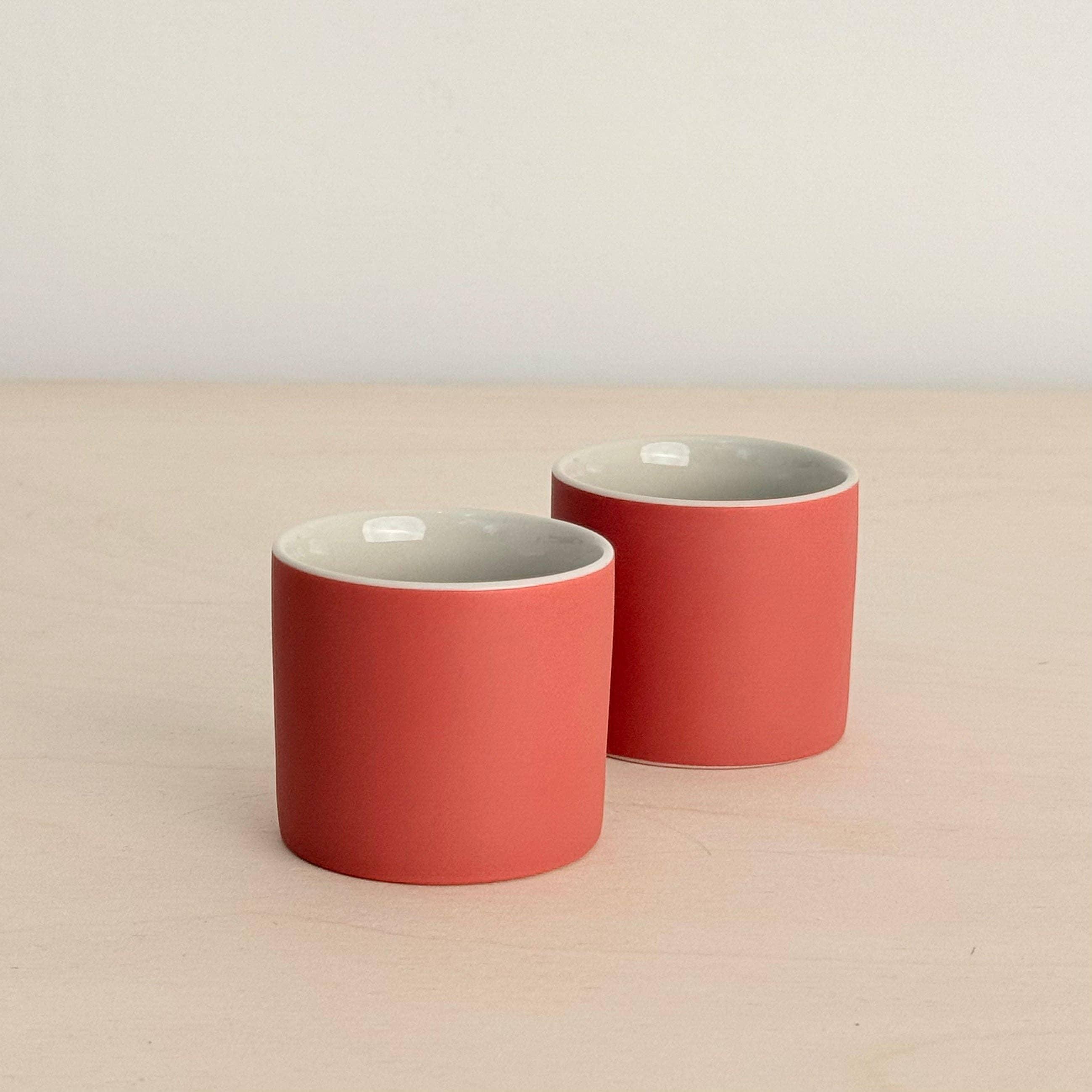 Fable coral ceramic cups set on light wood surface, minimalist design, premium tableware