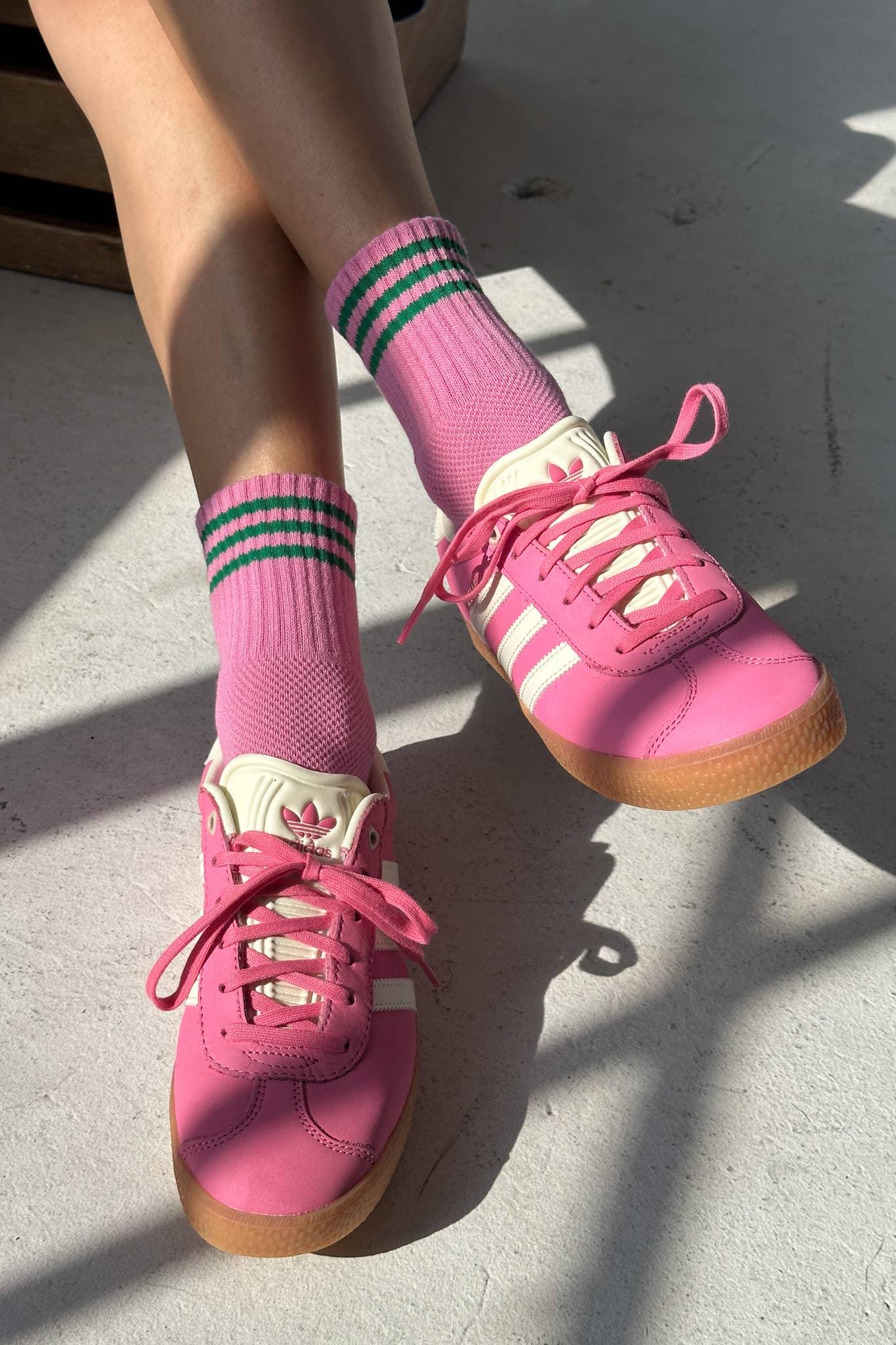 Adidas pink leather sneakers with white stripes and gum sole, worn with pink and green socks