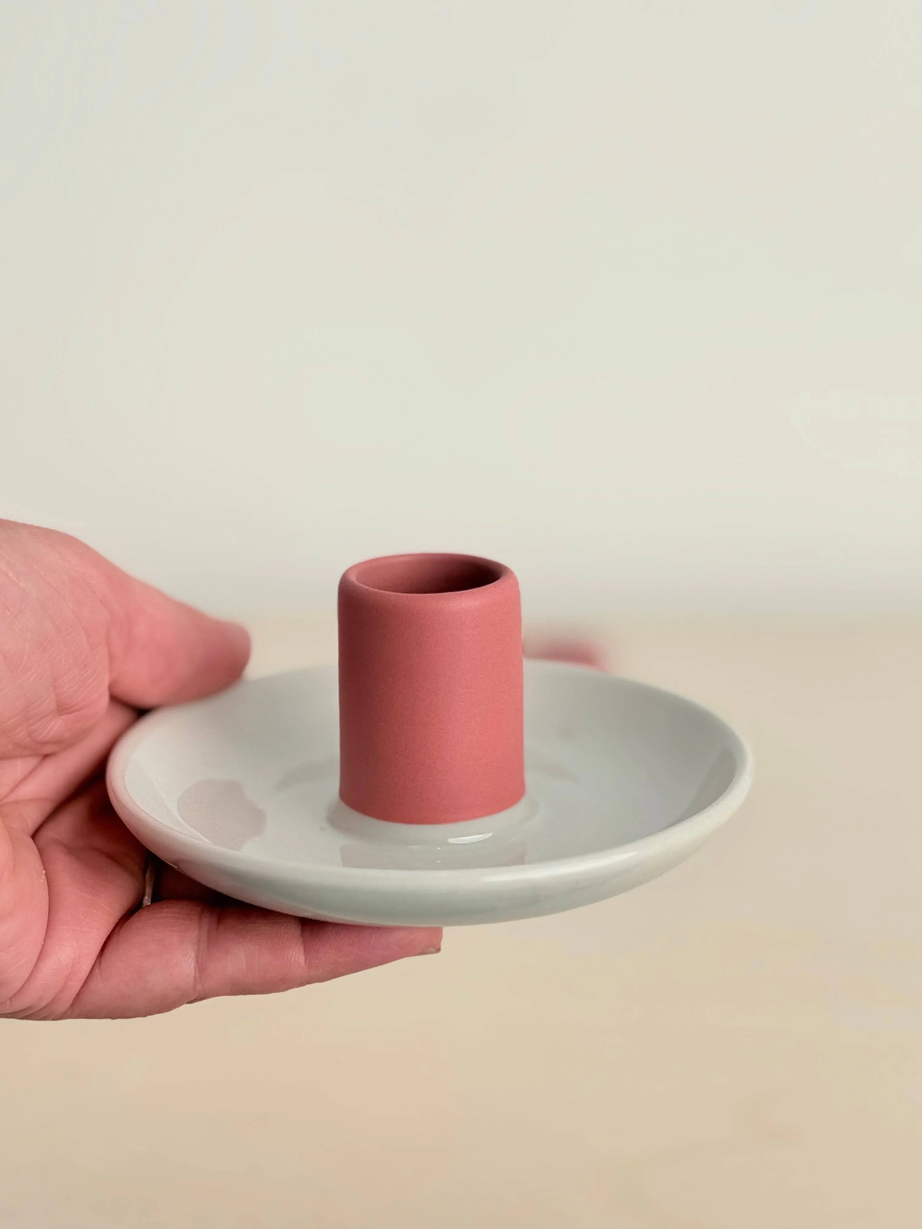 Fazeek ceramic candle holder in matte pink and glossy white, held in hand