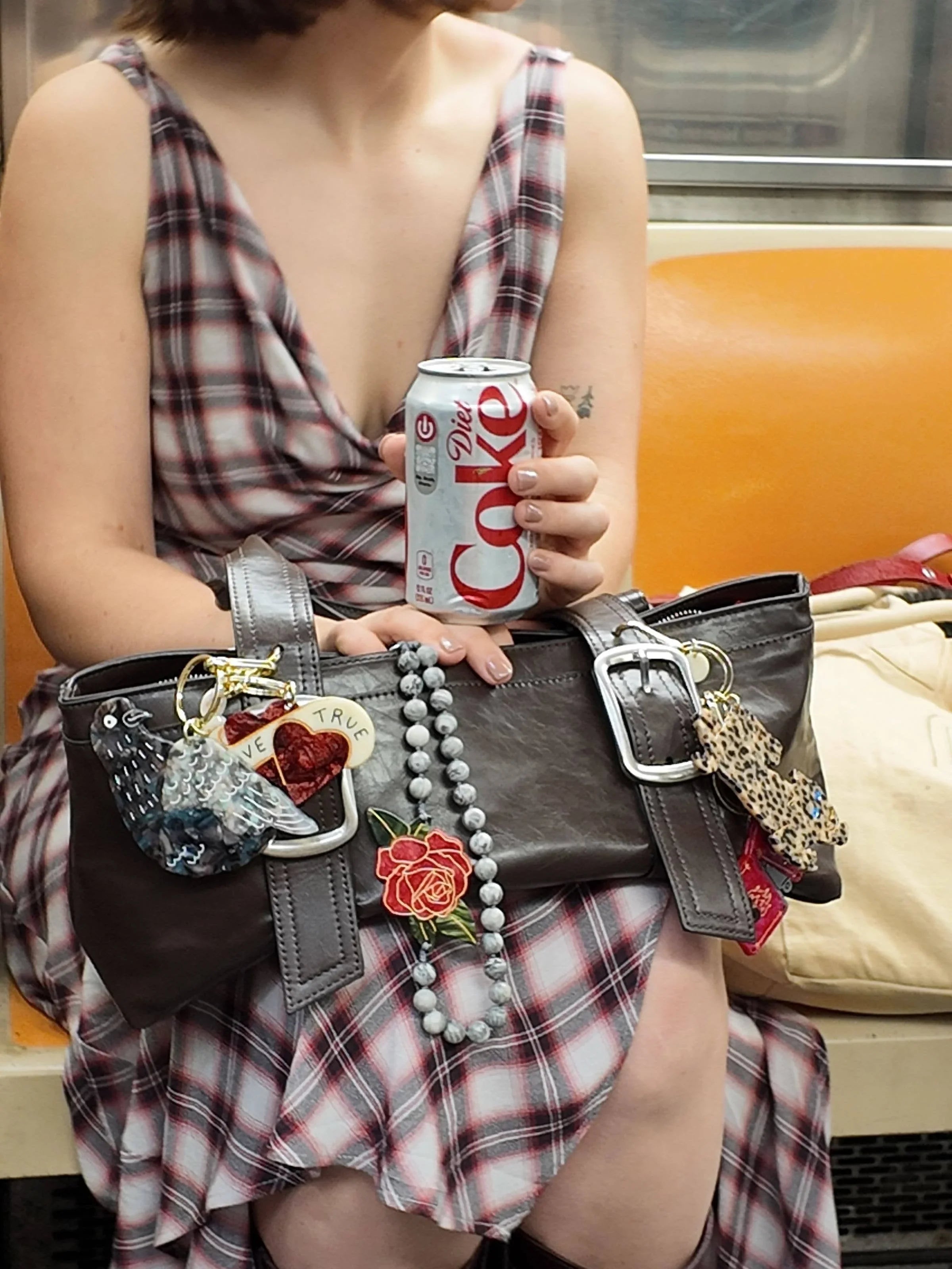 Diet Coke can, plaid dress, brown leather handbag with silver buckles and decorative charms