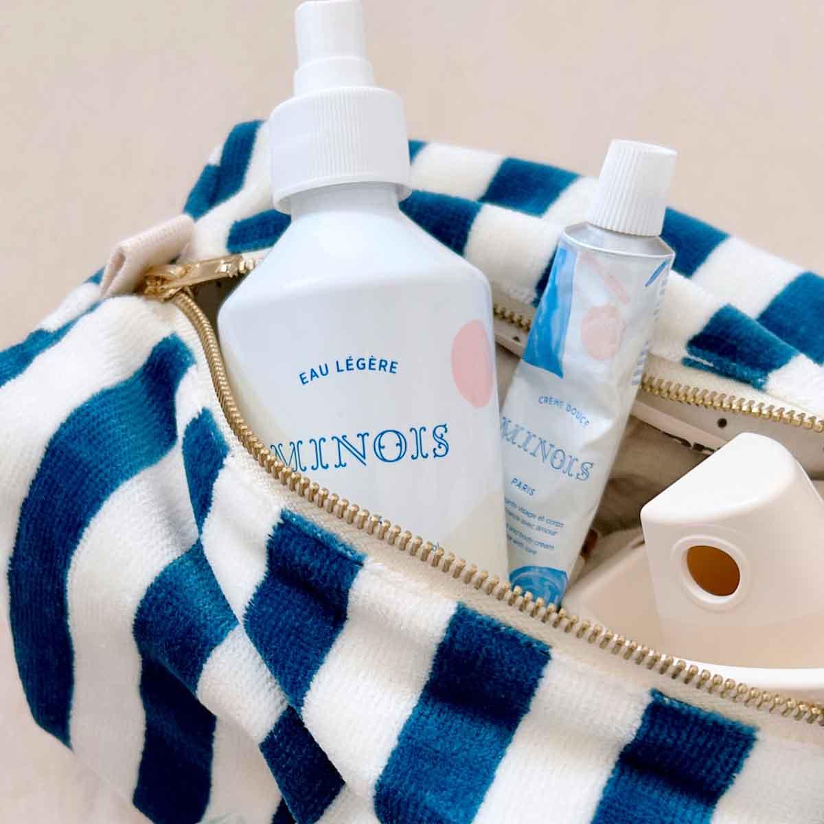 Minois Paris skincare set with white and blue bottles in a blue striped fabric pouch