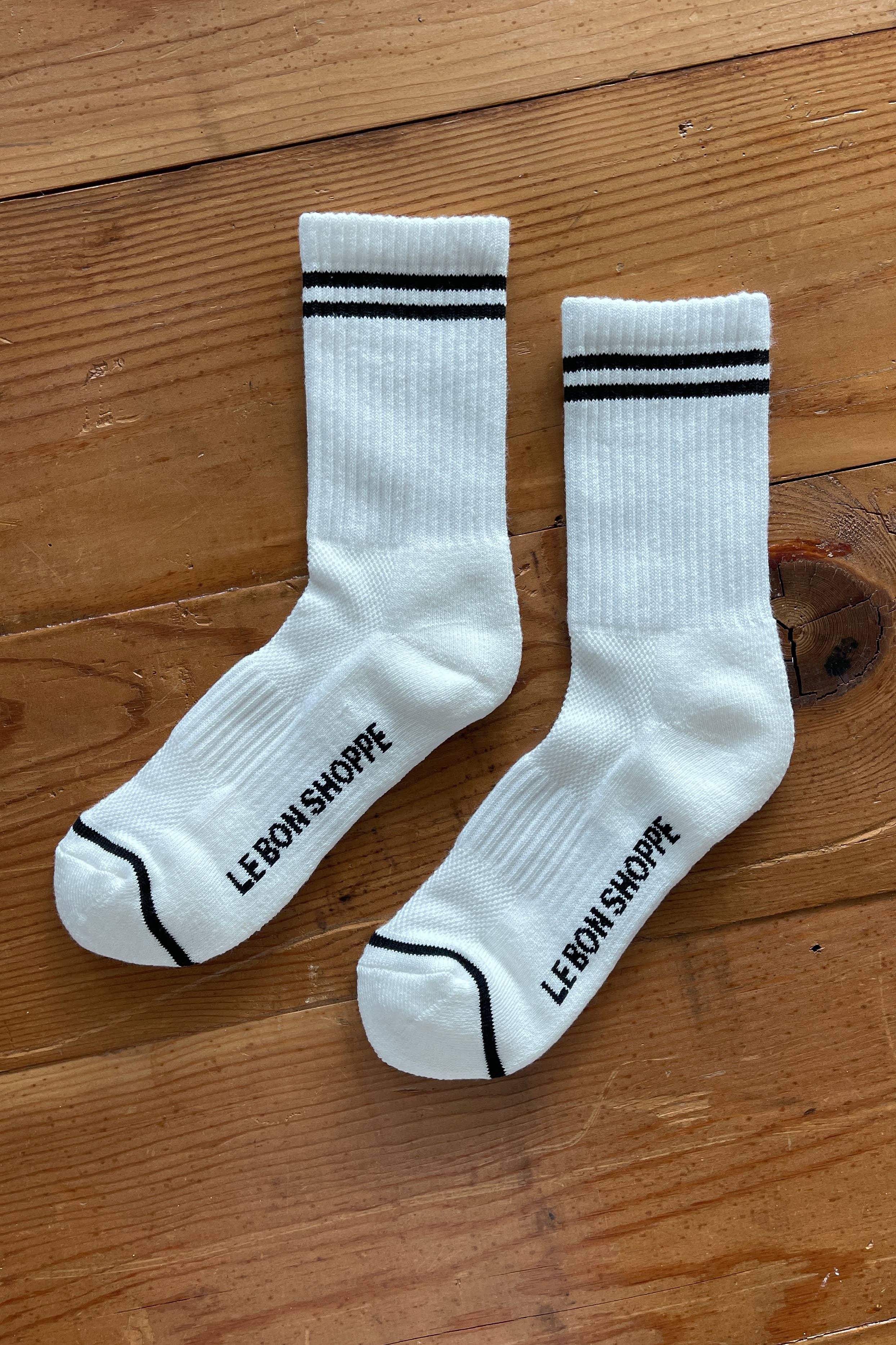 Le Bon Shoppe white cotton crew socks with black stripes and logo on wooden floor