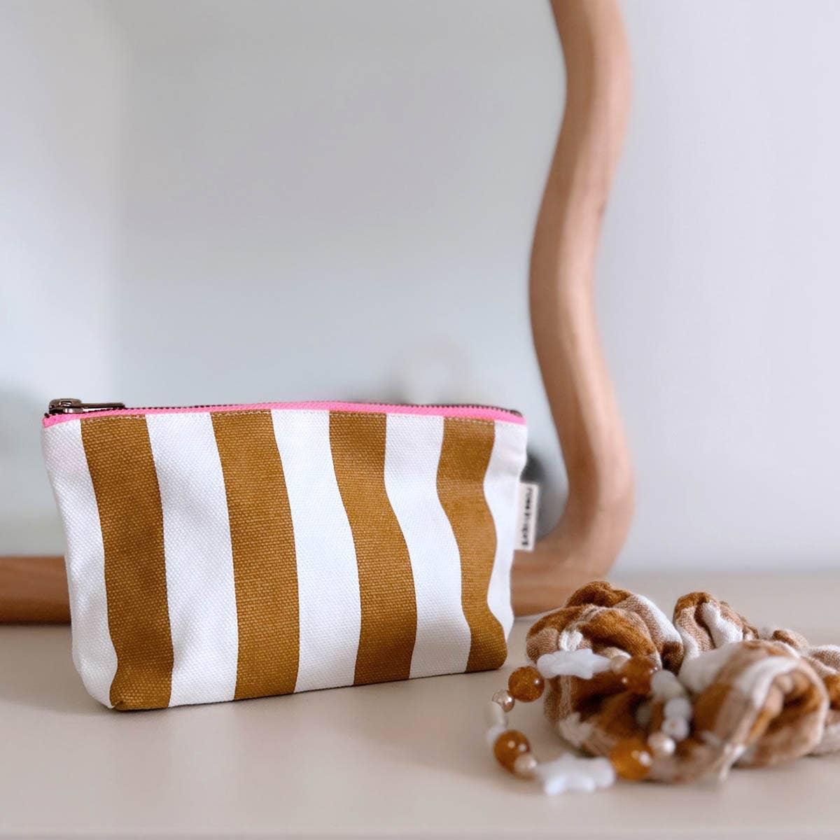 Kilele Studio canvas pouch, brown and white stripes, pink zipper, on a modern dresser