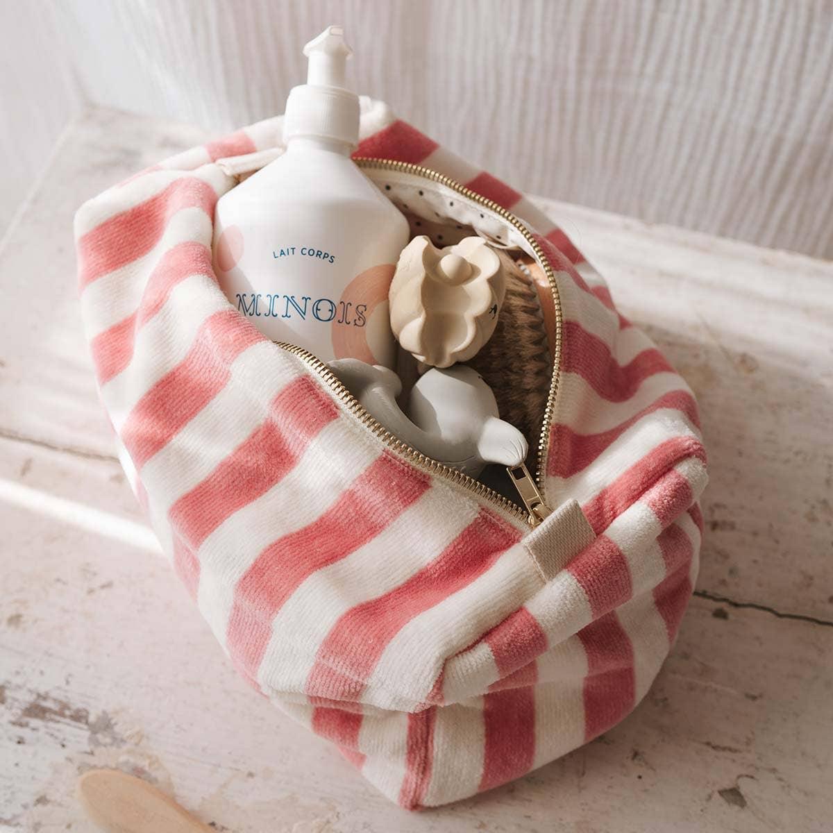 Minois striped cotton toiletry bag pink and white holding toiletries on wood surface